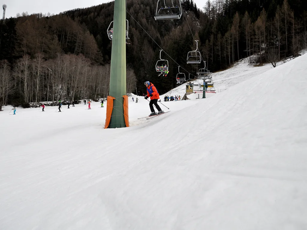 Skifahrerin in rosa Jacke quert den Hang.